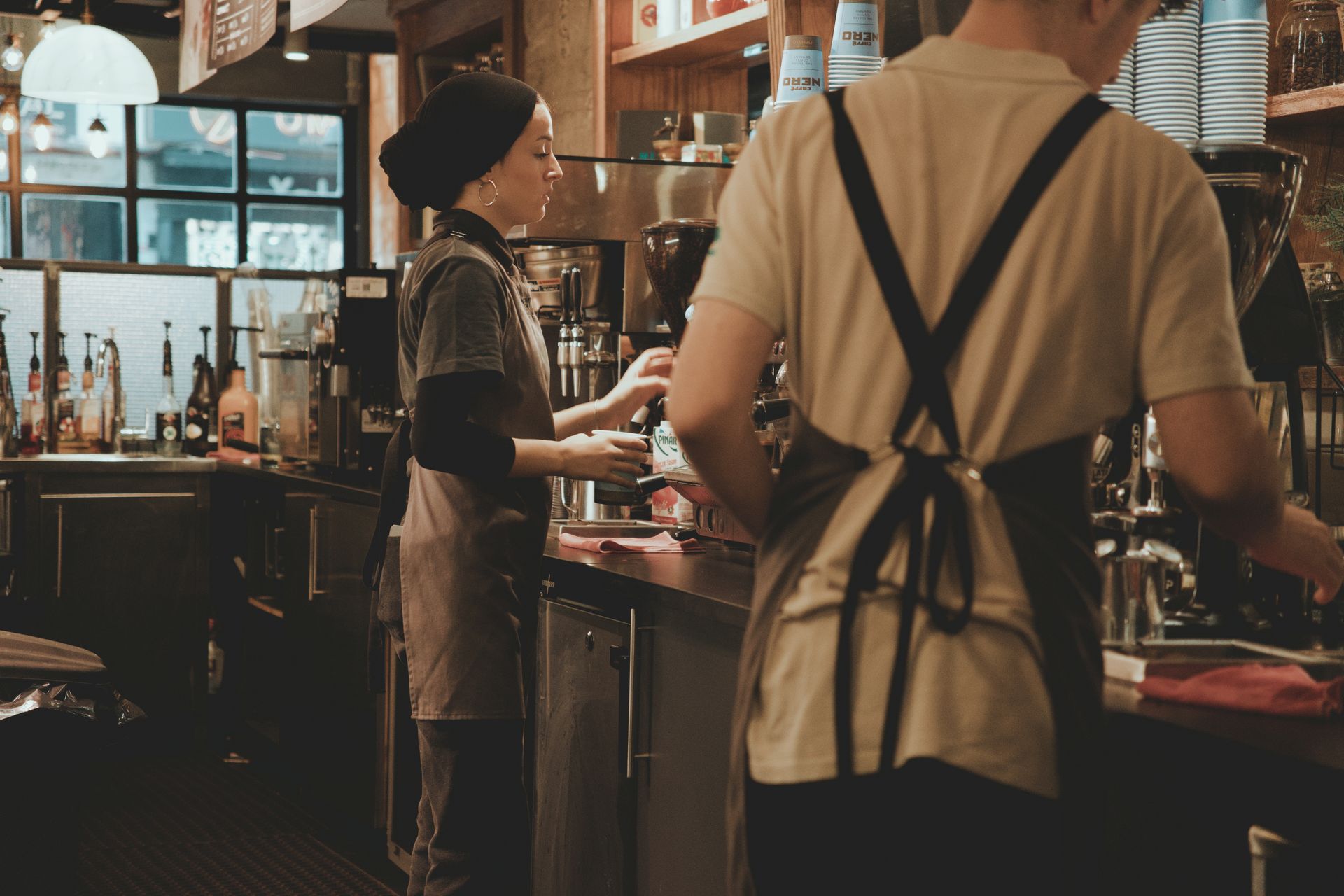 Two baristas working behind a coffee bar